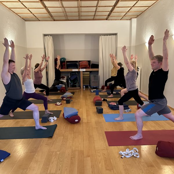 Mehrere Menschen in einem Yogaraum praktizieren Yoga